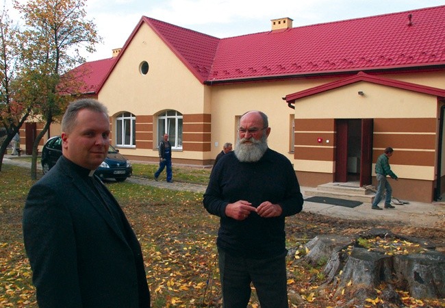 Prace remontowe wciąż trwają. Przed odnowionym ośrodkiem ks. Robert Kowalski  i Wojciech Dąbrowski