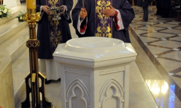 Bp Henryk Tomasik dokonuje obrzędu poświęcenia marmurowej chrzcielnicy