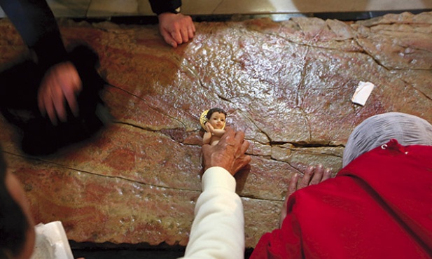  17 marca 2013, Izrael. Pielgrzym kładzie figurkę Dzieciątka Jezus na Kamieniu Namaszczenia w bazylice Grobu Pańskiego w Jerozolimie