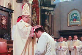  Arcybiskup Sławoj Leszek Głodź nakłada dłonie na głowę wyświęcanego diakona,  przekazując mu moc Ducha Świętego