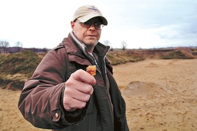 Archeolog Paweł Wiktorowicz z kawałkiem krzemiennego noża na miejscu wykopalisk w Lubomi