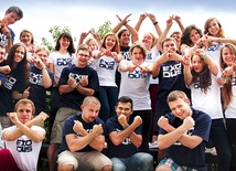 Młodzi wraz z profesjonalnymi aktorami w koszulkach promujących wydarzenie pokazują znak „X”, czyli „exodus” 