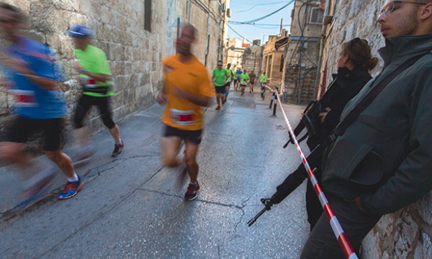 13.03.2015, Jerozolima. Uczestnicy piątego jerozolimskiego maratonu mijają patrol izraelskiej policji. Wzięło w nim udział 25 tysięcy ludzi z 60 krajów. 