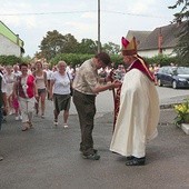 Bp Rudolf Pierskała wita przed kościołem przewodnika z pielgrzymami