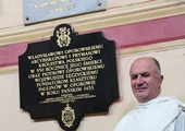 O. Czesław Matras w oporowskim kościele, nad nim tablica upamiętniająca o. Augustyna Kordeckiego
