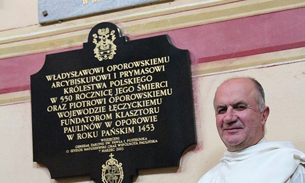 O. Czesław Matras w oporowskim kościele, nad nim tablica upamiętniająca o. Augustyna Kordeckiego