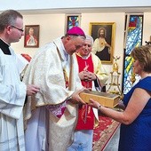 Parafianie składają w darze ołtarza pustą księgę na zapisywanie nowych łask wyproszonych przez Maryję