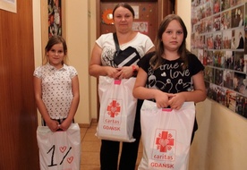 Pani Michalina do Centrum Wolontariatu Caritas na ul. Jesionowej przyszła z dwiema córkami - Julią i Amelią. Obie dziewczynki bardzo cieszą się z ogromnych reklamówek, w których znajdują się zeszyty, farby, bloki i inne przydatne w roku szkolnym przybory