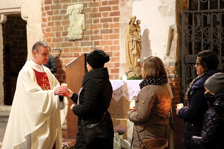 Rodzice przekazują ks. Piotrowi Nowakowi zapalone znicze, których płomień symbolizuje utracone dziecko