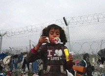  17.03.2016. Grecja. Dziewczynka, imigrantka z Syrii, puszcza bańki mydlane tuż przy ogrodzeniu obozu dla uchodźców.