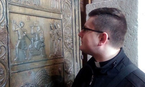 Al. Mateusz Czernik przypatruje się scenie śmierci św. Wojciecha przedstawionej na drzwiach gnieźnieńskich