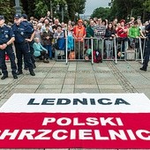 	Flaga Polski z zawołaniem lednickim została rozłożona tuż  przy figurze Matki Bożej. W tle pielgrzymi z diecezji gliwickiej.