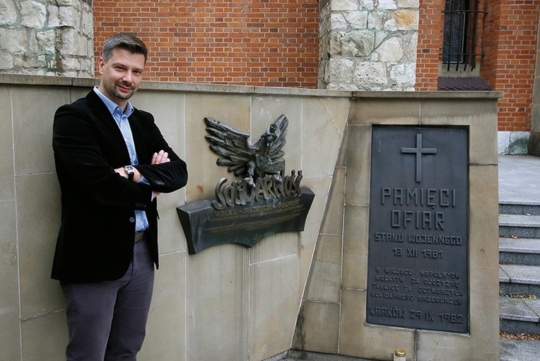 Dr hab. Filip Musiał przed tablicami „Pamięci ofiar stanu wojennego” oraz z okazji 25-lecia powstania „Solidarności”, które stoją przed bazyliką.