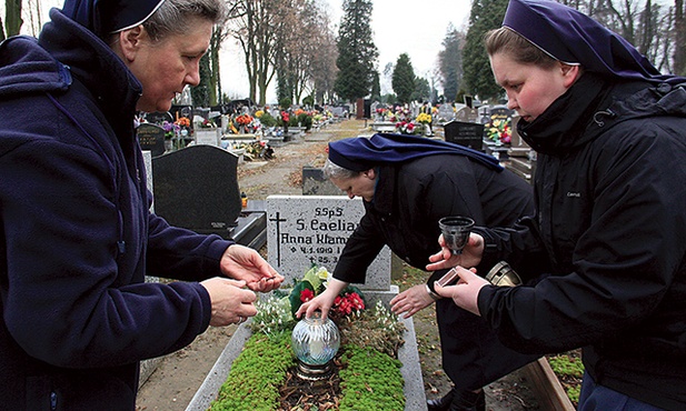 Od lewej: s. Dolores Zok, s. Renata Sałamacha i s. Marta Poświatowska zapalają znicz na grobie s. Caeliany.