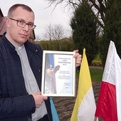 Ks. Mariusz Wilk z dyplomem potwierdzającym przyznanie nagrody wojewódzkiej.