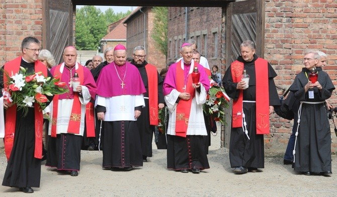 Biskupi i franciszkańscy współbracia św. Maksymiliana podchodzą do Ściany Śmierci obok bloku 11.