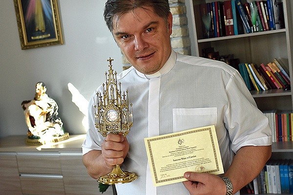 Ks. Zbigniew Chromy trzyma relikwie świętej z Umbrii i certyfikat potwierdzający ich autentyczność.