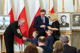 Magdalena Zarzycka odbiera notę identyfikacyjną swojej mamy Stefanii. Podczas uroczystości towarzyszą jej wnukowie. – Chcę, żeby chłopcy zapamiętali tę chwilę na całe życie – mówi pani Magdalena.