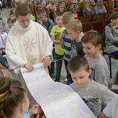 Ks. Tomasz Orłowski odwija zwój Listu do Rzymian, spisany przez dzieci i młodzież radomskiej katedry