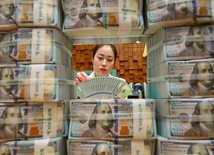 Urzędniczka w banku sprawdza, czy 100-dolarowe banknoty są fałszywe. 
4.05.2018 Seul, Korea Płd.
