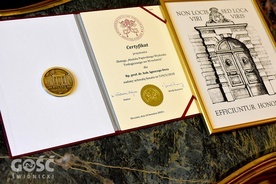 Dokumenty i medal, które otrzymał biskup na 50-lecie PWT we Wrocławiu.