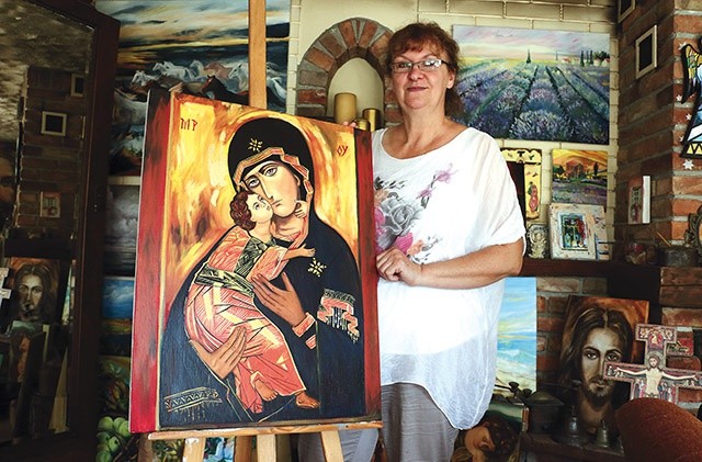 ▲	Małgorzata Krzemińska przy wizerunku Matki Bożej Włodzimierskiej. Choć w pracowni najwięcej jest ikon, artystka maluje także portrety i pejzaże. Najczęściej dla znajomych. 