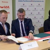 Umowę podpisują (od lewej): Artur Ludew i Rafał Rajkowski. Z prawej Iwona Czarnota, skarbnik Szydłowca