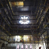 ▲	Wnętrze odzyskuje historyczny wygląd: południowa ściana transeptu w trakcie transferu wtórnych malowideł, zasłaniających oryginalne anioły. U góry w otworze podestu widać dekoracje stropu po renowacji.