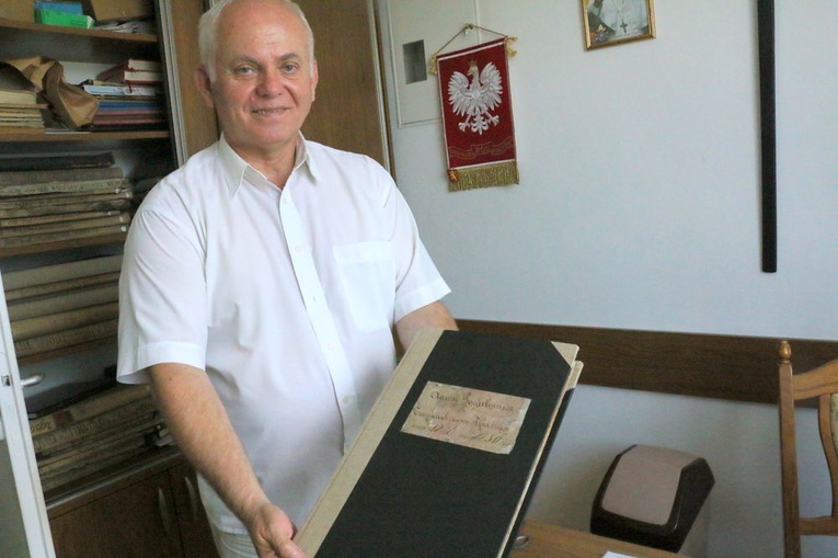 Ks. Andrzej Maleszyk pokazuje stare księgi, które opowiadają o historii kościoła.