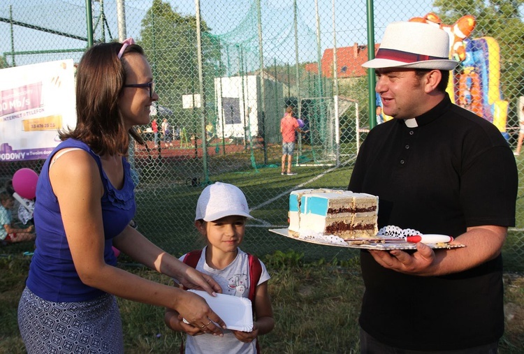 Ks. Jerzy Kajzar - kierowca parafianego autobusu z małą Mają (i jej mamą) - zwyciężczynią licytacji tortu autobusowego.