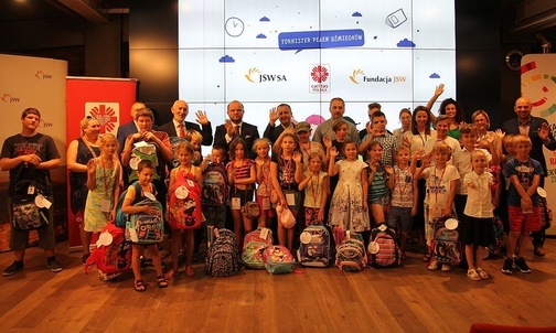 Obdarowane tornistrami dzieci ze swoimi rodzicami, dyrektorami Caritas z Bielska-Białej i Katowic, szefostwem Jastrzębskiej Spółki Węglowej i pracownikami Fundacji JSW.