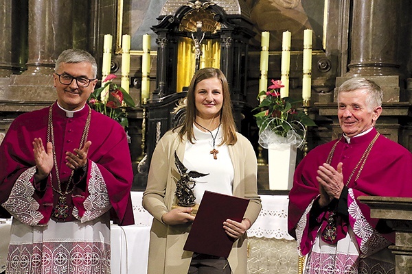 ▲	Małgorzata Białczak  ze statuetką i gratulujący jej wyróżnienia księża: Jan Krajczyński  (od lewej) i Wiesław Gutowski.