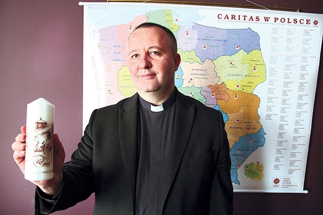▼	Ksiądz Łukasz Stawarz z tegoroczną świecą Caritas.