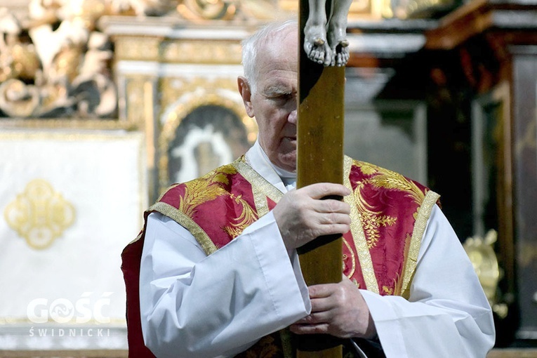 Cierpienie i skupienie wymalowane na twarzy biskupa ukazującego wiernym krzyż.