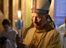 Biskup niosący świecę z zapalonym ogniem symbolizującym zwycięstwo życia nad śmiercią.