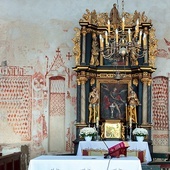 ▼	Na ścianie wschodniej (po lewej) widoczny jest napis „Maria”, pod nim polichromia imitująca tkaninę otacza niezamalowany kształt, który mogła wyznaczyć przysunięta do ściany Pieta.