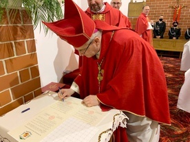 Biskup podpisujący stosowne dokumenty związane z poświęceniem nowej kaplicy.