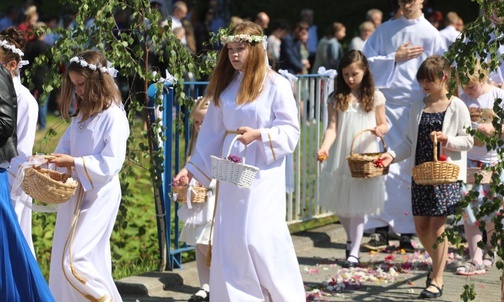 Dziewczynki, które kilka dni temu po raz pierwszy przystąpiły do Komunii Świętej, sypały kwiaty przed kapłanem niosącym monstrancję.