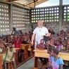 Ks. Piotr Boraca z dziećmi w nowej sali szkolnej.