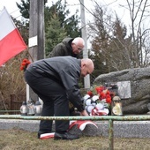 Składanie kwiatów przed pamiątkową tablicą.