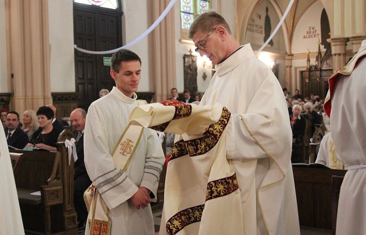 Ks. proboszcz Jan Duraj pomaga nałożyć dalmatykę diakonowi Mateuszowi Kuryle.