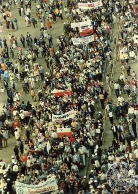	12 czerwca 1987 r. Trwa pokojowa demonstracja na ulicach Gdańska, zorganizowana po papieskiej Mszy św. na Zaspie. Na fotografii widać tłum ludzi z prosolidarnościowymi flagami i transparentami.