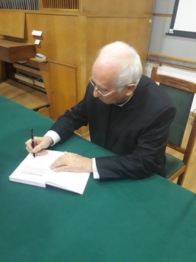 Biskup Andrzej F. Dziuba podpisuje jubileuszową książkę.