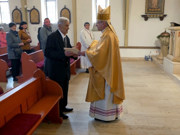 Biskup składający odchodzącemu na emeryturę kościelnemu gratulacje.