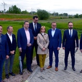 Uczestnicy konferencji na tle terenów w pobliżu linii kolejowej, na których zostanie zbudowana nowa nitka trasy z południa na północ Radomia.