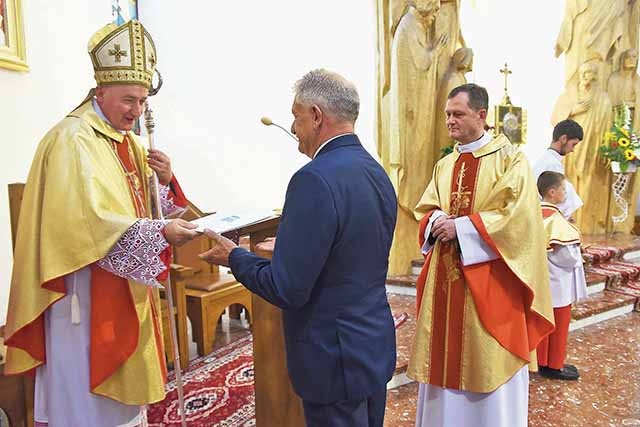Bp Andrzej Jeż przekazuje papieski dokument wójtowi Janowi Dydzie.