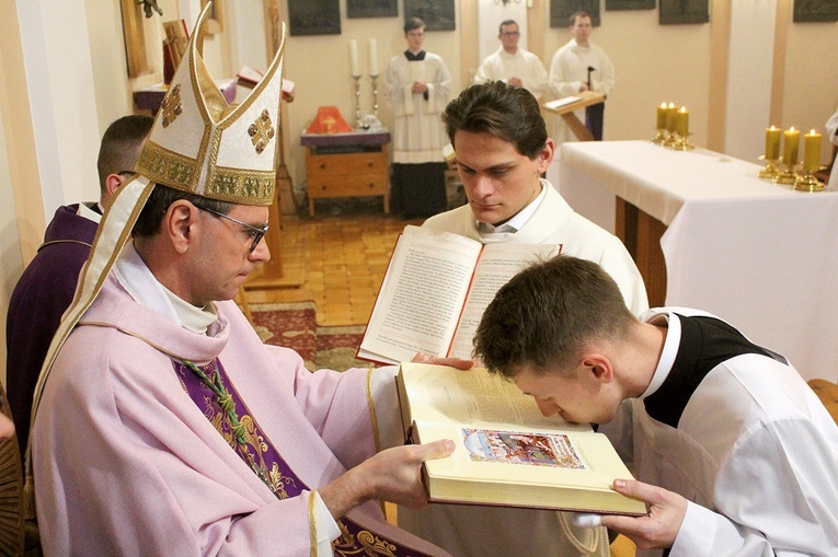 Klerycy podchodzili do biskupa, który przekazywał im otwartą księgę Pisma Świętego.