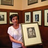  Dorota Rogoż z Muzeum Historii Katowic z autoportretem Pawła Stellera; w tle jego grafiki o śląskiej tematyce