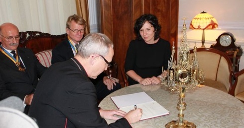 Bp Piotr Libera podpisuje protokół z przyjęcia zabytkowej monstrancji