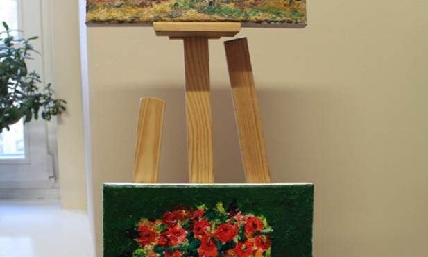 Na obrazach Anny Szcześniak dominują motywy kwiatowe oraz pejzaże i chaty regionu łowickiego
